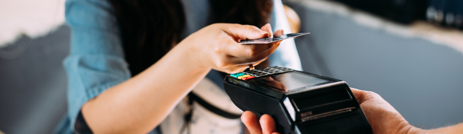 someone holding a card up to a payment processor 